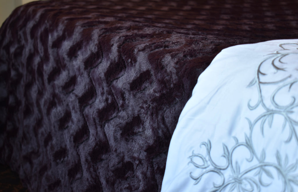 Textured dark brown fabric and white embroidered pillow with floral patterns.