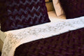 Close-up of a textured purple blanket with a white embroidered runner on a bed.