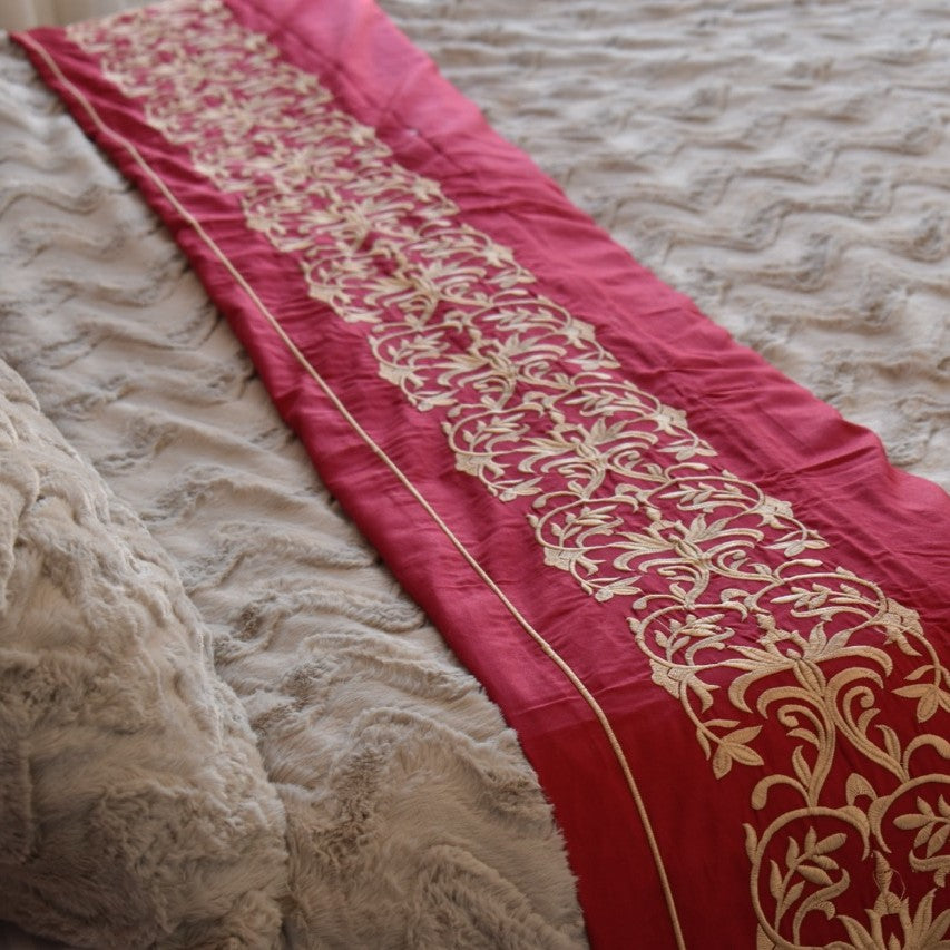 Red fabric with gold embroidery on a textured surface